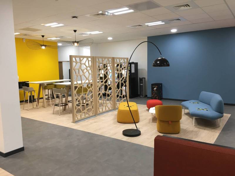 Aménagement cafétéria multifonctionnelle avec les canapés, fauteuils, tables basses et poufs de la collection OPENEST d'HAWORTH design Patricia URQUIOLA